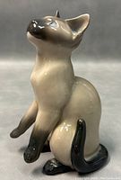 Side view of the porcelain Siamese cat figurine showing its detailed glaze and posture.