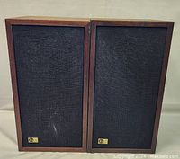 Front view of both speakers showing black cloth grilles and gold-tone EPI logo badges
