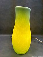 Front view of frosted green glass lamp illuminated, showing warm glow and marbled pattern.