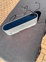 Top and angled view of FRESKO electric bag sealer on a black surface outside, showing power cord and glossy top.