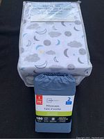 Twin sheet set packaged with white background and gray clouds, moons, and stars in blue and yellow.