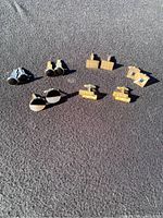 Six pairs of cuff links displayed on a fabric surface, showing variety in style and material color.