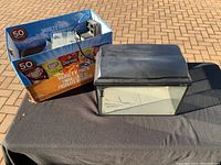 Small rectangular glass fish tank with black lid shown beside the original packaging box.