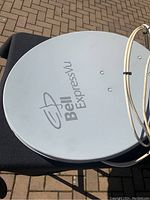 Close-up of white Bell ExpressVu satellite dish showing logo and surface wear.