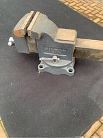 Photo showing full side view of the grey Wilton tabletop vice on a dark surface outdoors.