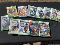 11 Xbox 360 game cases displayed on black surface, showing front cover art and titles of assorted games.