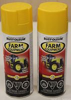 Front view of two Rust-Oleum Farm Equipment spray paint cans with yellow caps.