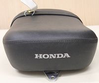 Front view of the black Honda motorcycle seat showing Honda logo and mounting tab.