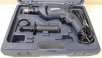 Mastercraft 1/2 inch electric hammer drill with auxiliary handle and power cord inside its plastic carrying case.