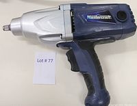 Side view of blue and silver Mastercraft 1/2" impact wrench with ergonomic handle and trigger, next to lot number card.