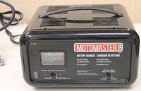 Front view of black plastic MotoMaster battery charger model BC133 with control panel and charging gauge visible