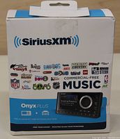 Front of the SiriusXM Onyx Plus box showing the brand, model, music channel logos, and image of the device