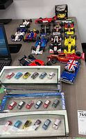 Group of 1:18 diecast IndyCar models and loose 1:72 and 1:16 Mini Cooper models displayed on a table