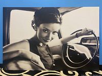 Front view of the large black and white canvas print showing a woman inside a car, holding steering wheel, with a vintage style