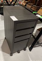 Front angled view of the file cabinet showing four drawers and casters.