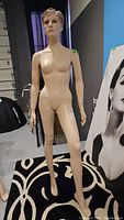 Full front view of female mannequin standing upright on circular stand.