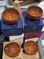Four Tenmoku glazed teacups displayed on top of their keepsake boxes.