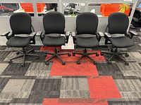 Front view of four black chairs in a row showing overall condition and alignment