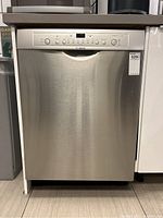 Full front view of closed dishwasher showing stainless steel exterior and brand logo
