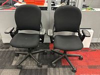 Two black Steelcase Leap chairs side by side facing camera in office setting