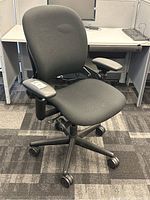 Steelcase Leap office chair front angled view showing black fabric seat and backrest, adjustable armrests, and caster wheels.