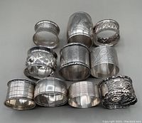 Full lot of 11 silver napkin rings showcasing various designs, engravings and finishes