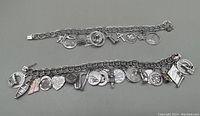 Two sterling silver charm bracelets side by side displaying numerous silver charms attached to each.