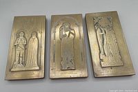 Three brass rubbing plaques arranged flat to show front detail with knight and lady effigies and inscriptions beneath.