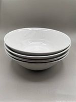 Stack of four white ironstone bowls showing the interior textured Athena pattern.