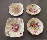 Four small decorative dishes shown together, floral and leaf patterns, different shapes and gold accents.