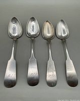 Four antique American coin silver tablespoons arranged side by side showing front of bowl and handles with monograms M.S.D. and J.P.W.