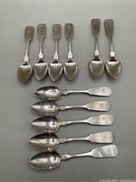 Top and bottom view showing all 11 teaspoons laid out in two rows, showcasing their shapes and finishes.