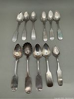 Eleven antique American coin silver teaspoons arranged in two rows showing different bowl shapes and handle styles.