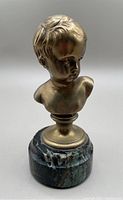 Front angle view of the unpatinated bronze child bust on marble base.