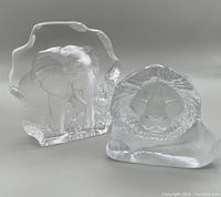 Elephant and lion lead crystal sculptures side by side on neutral background showing each piece's front and side details.