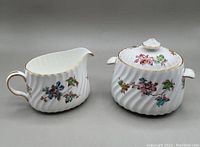 Minton Vermont pattern creamer and covered sugar bowl with handles and floral pattern, gold trimmed edges.