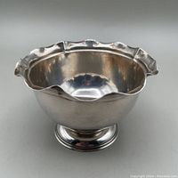 Front and side view of small sterling silver bowl with scalloped rim and rounded footed base.