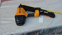 Full view of Bostitch nailer laid on surface with measuring tape
