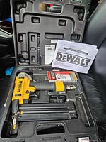 DeWalt brad nailer and accessories securely placed in molded plastic carrying case showing the full kit including the tool, nails, and manual.
