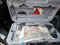 Open case showing Dremel Multi-Max MM20 tool, plastic bag with metal attachments, and sanding pads.