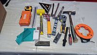 Photo of assorted hand tools including hammer, mallet, nail pullers, hammer tacker, levels, screwdrivers, tape measure and square.