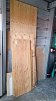Photo showing several plywood sheets of various sizes leaning against a wall in a storage unit