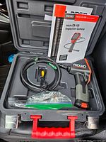 Full view of the Ridgid micro CA-100 inspection camera kit inside the opened hard plastic carrying case with accessories and manual
