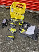 Overview of Ryobi tools, charger, battery, crate, and bag arranged on ground