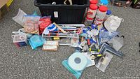 Overview of tiling supplies bin with tools, jars of spacers and hand tile cutter visible