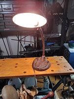 Image showing lamp illuminated on wooden workbench in workshop environment.