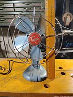 Front view showing fan blades, red center logo, and size reference with ruler