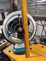 Side view of the vintage Vornado fan with ruler to show size approximately 11 inches tall.