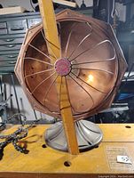 Full view of the vintage heater converted to lamp with visible metal base, octagonal cage with wires and bulb inside.