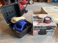 Blue Simoniz buffer with black carrying case and wool polishing pad, seen on garage floor
